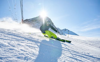 skifahrer auf piste fährt bergab und carvt