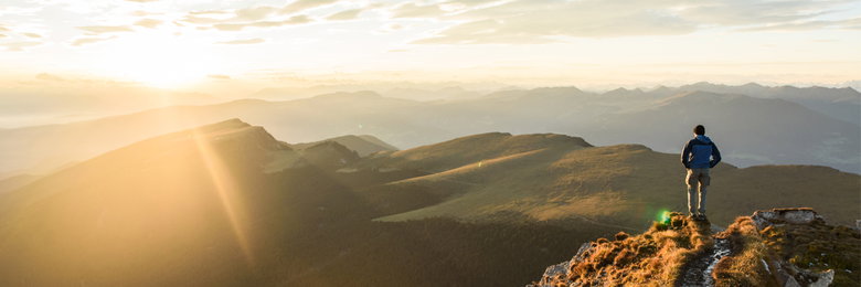 Wanderer mit warmer Bekleidung auf einem Berggipfel.