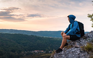 Wanderer mit Hoody genießt am Abend die Aussicht.