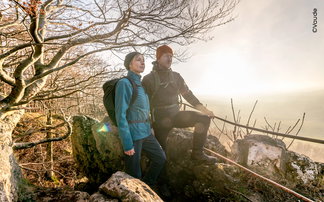Zwei Wanderer mit warmer Bekleidung genießen eine winterliche Aussicht.