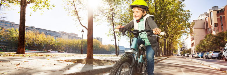 Kind mit gelben Helm auf dem Fahrrad