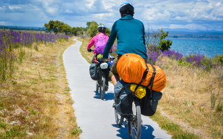 Fahrradfahrer mit Trekkingrad und Gepäck fahren an einem See entlang