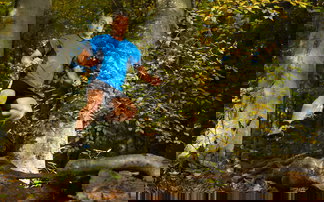 Trailrunner springt im Wald auf dem Weg hinab