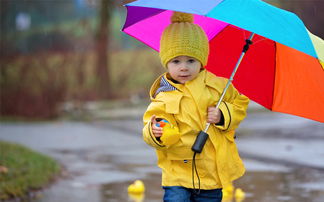 Mädchen in gelber Jacke mit Regenschirm