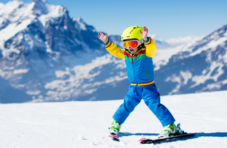 Kleines Kind in blauem Skianzug beim Skifahren