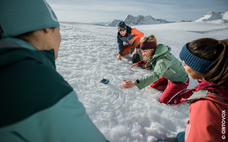 Gruppe Menschen, die mit LVS-Gerät im Schnee hantiert